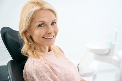 Smiling patient at a dental clinic during a follow-up visit after All-on-4 dental implant treatment.