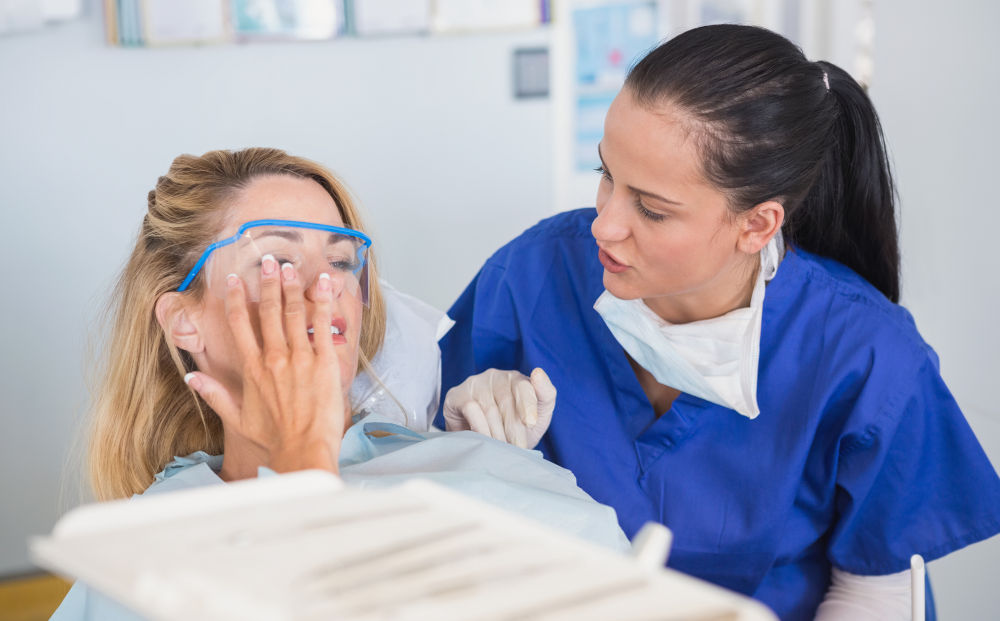 Woman applying cold compress to jaw during dental emergency — first aid before dentist appointment in Markham